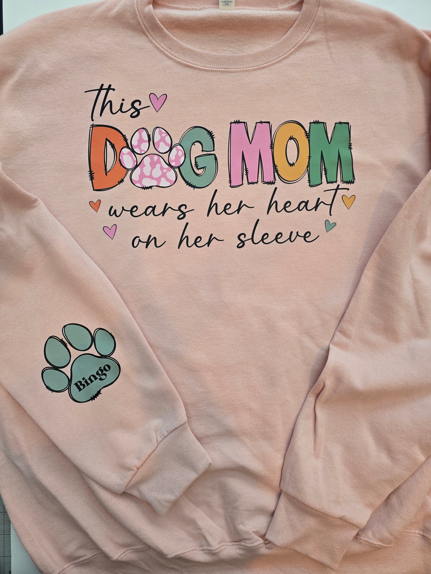"This Dog Mom Wears Her Heart On Her Sleeve"In BLUSH PINK Personalized Dog Name Sweatshirt in Sweet Cream| Custom Dog Mom Sweatshirt – Personalized Paw Prints & Names