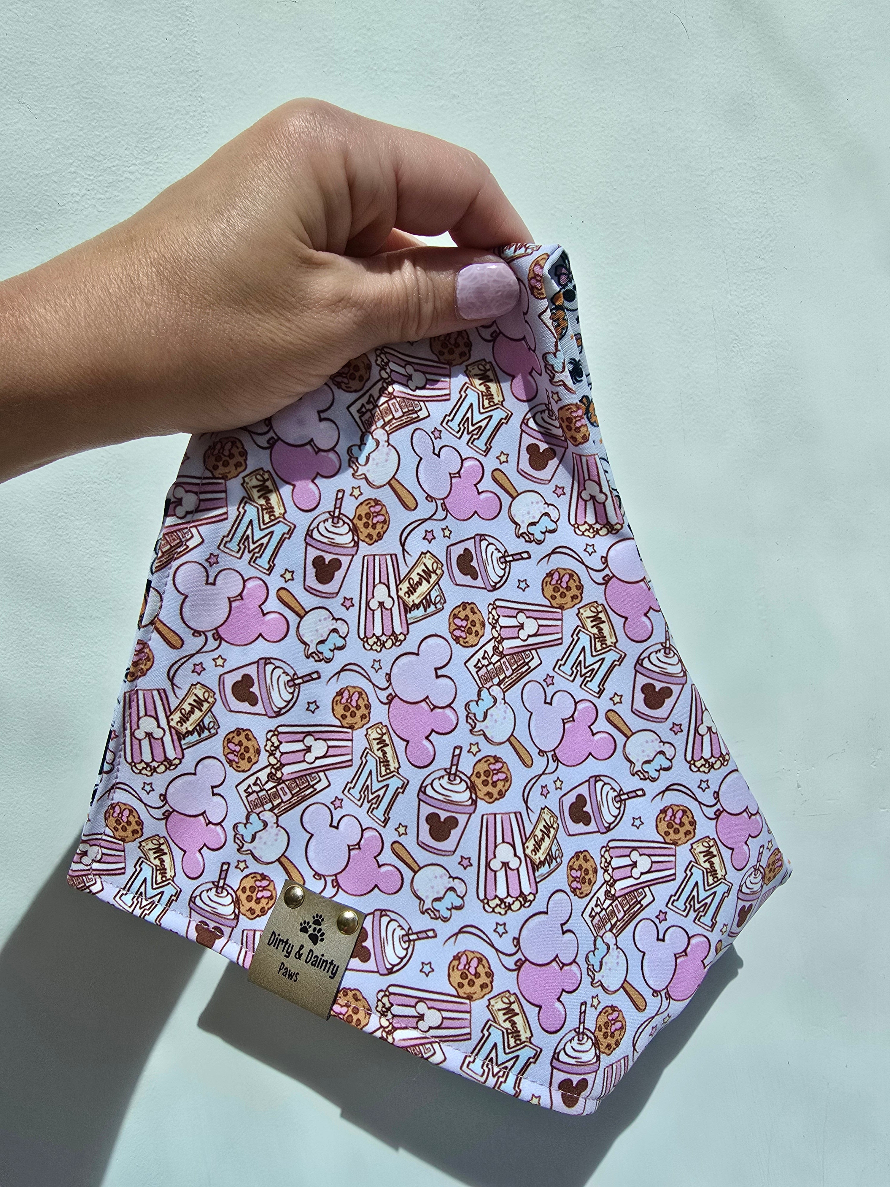 Close-up of Magical Treats Disney-inspired dog bandana with faux leather Dirty & Dainty Paws tag, made with Zoomie Proof™ polyester fabric.