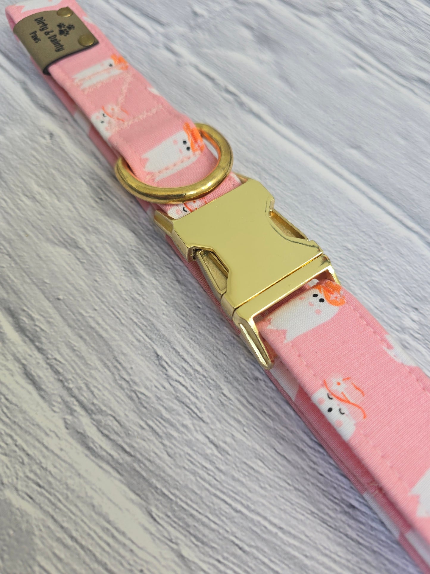 Pink dog collar featuring cute ghosties wearing cowboy hats. The collar includes a gold metal buckle and a Dirty & Dainty Paws branded tag. Ideal for pet owners looking for a stylish and spooky accessory