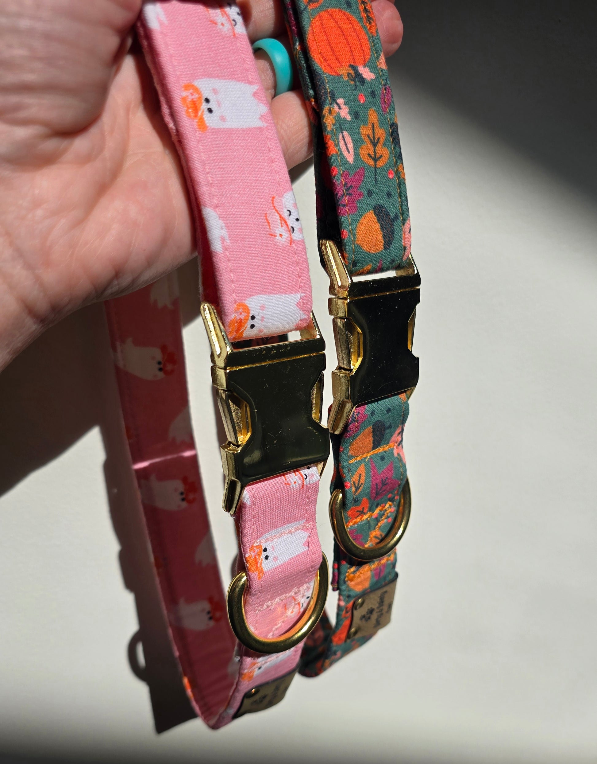 Pink dog collar featuring cute ghosties wearing cowboy hats. The collar includes a gold metal buckle and a Dirty & Dainty Paws branded tag. Ideal for pet owners looking for a stylish and spooky accessory