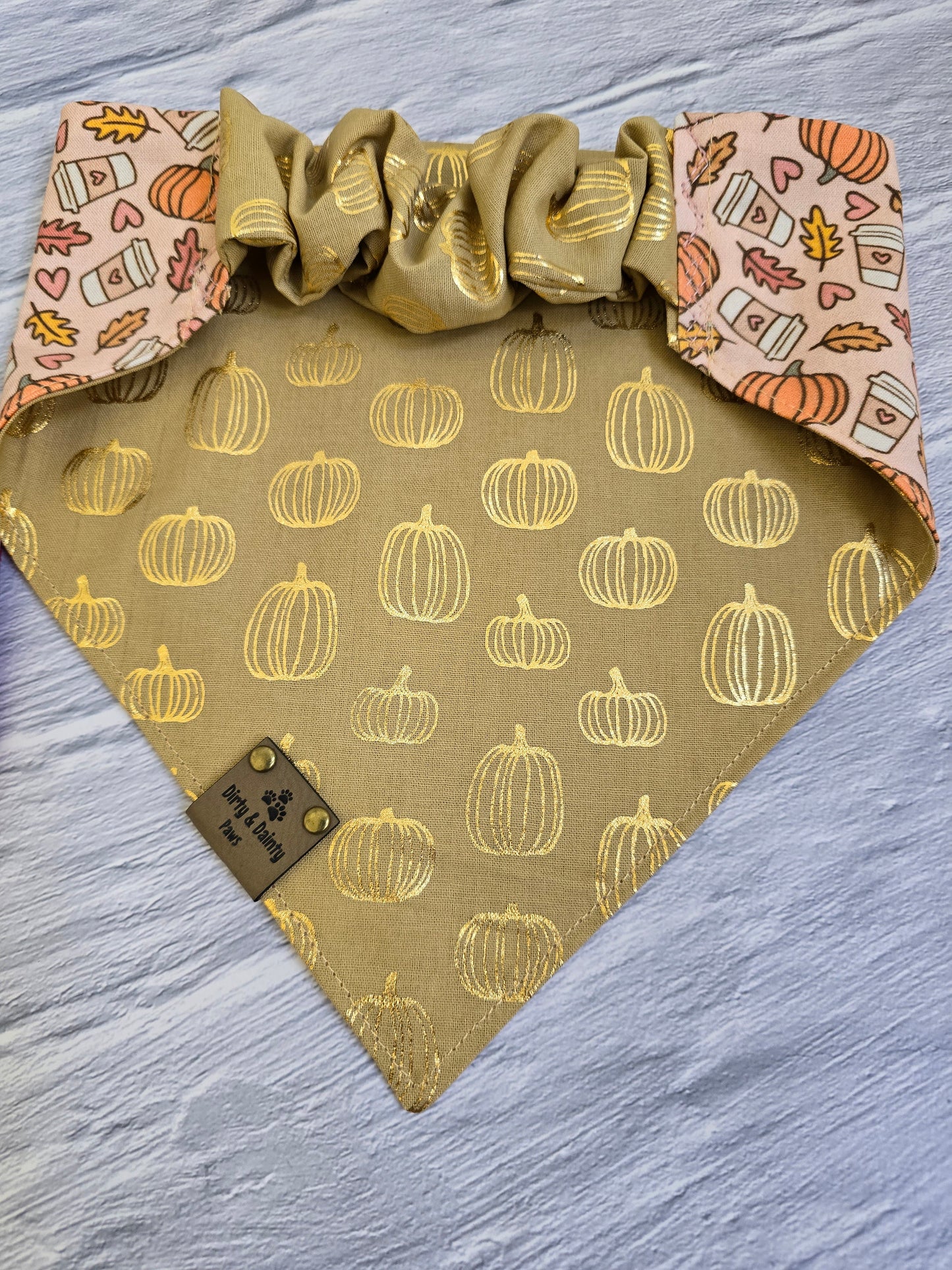 Dog wearing a reversible bandana with a pumpkin design and gold foil pumpkins from Dirty and Dainty Paws.