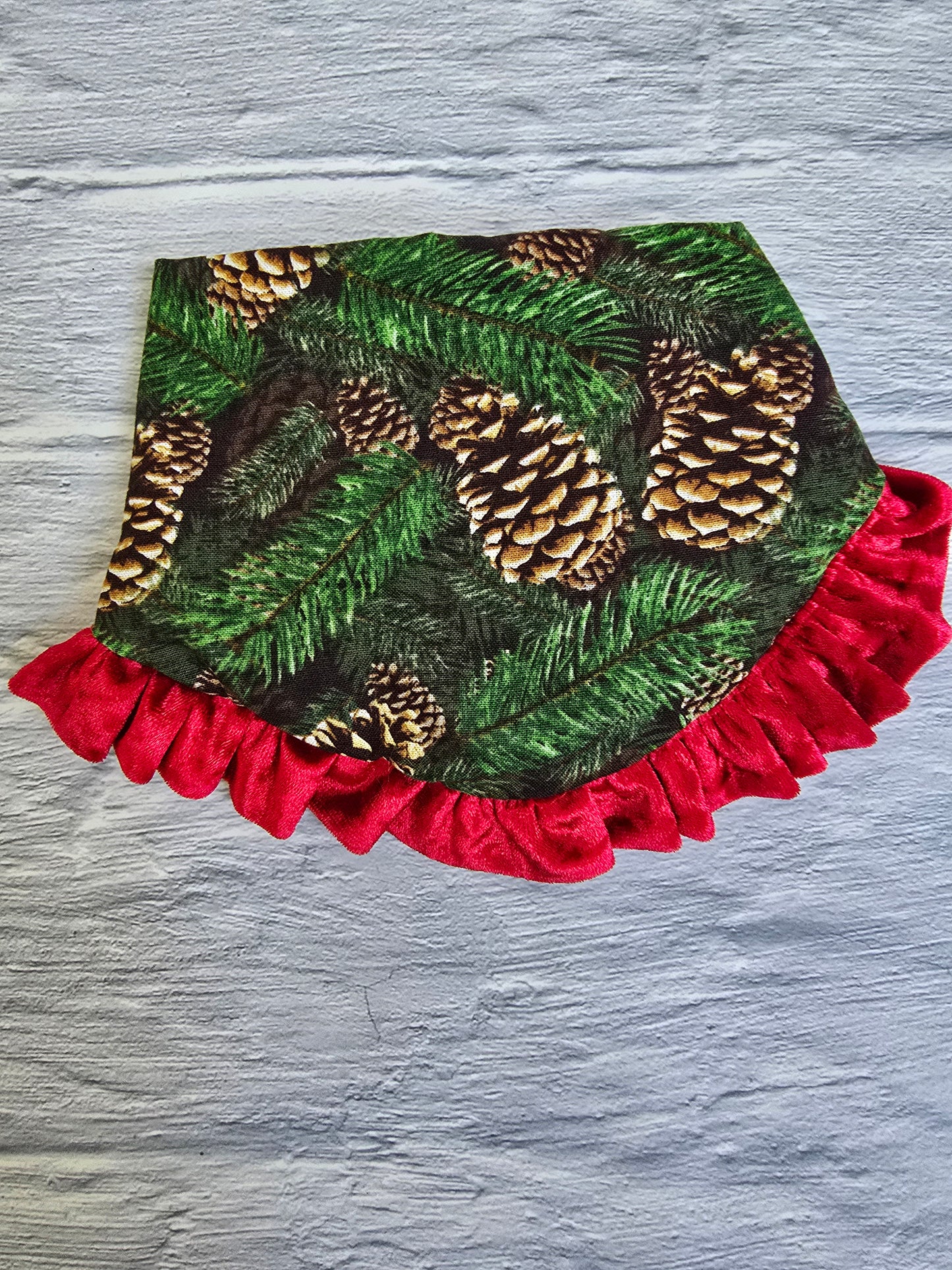  Dog wearing a Pinecone Ruffle Scrunchie Dog Bandana with a pinecone and evergreen design, accented by a red shimmering ruffle trim