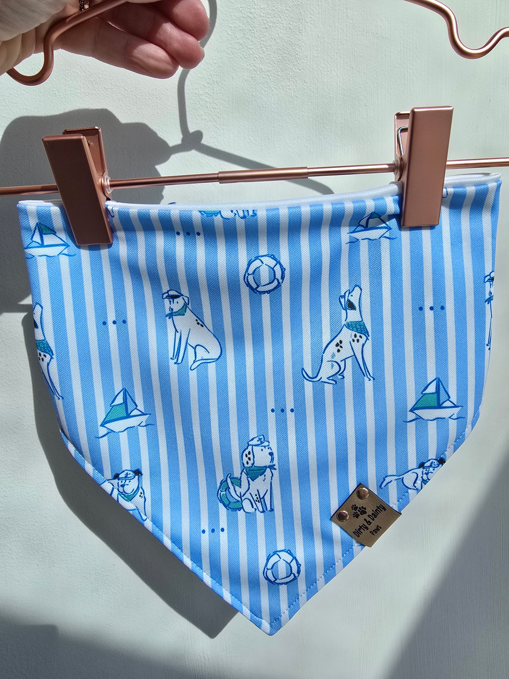 Blue striped bandana with dog patterns hanging on a clothesline.