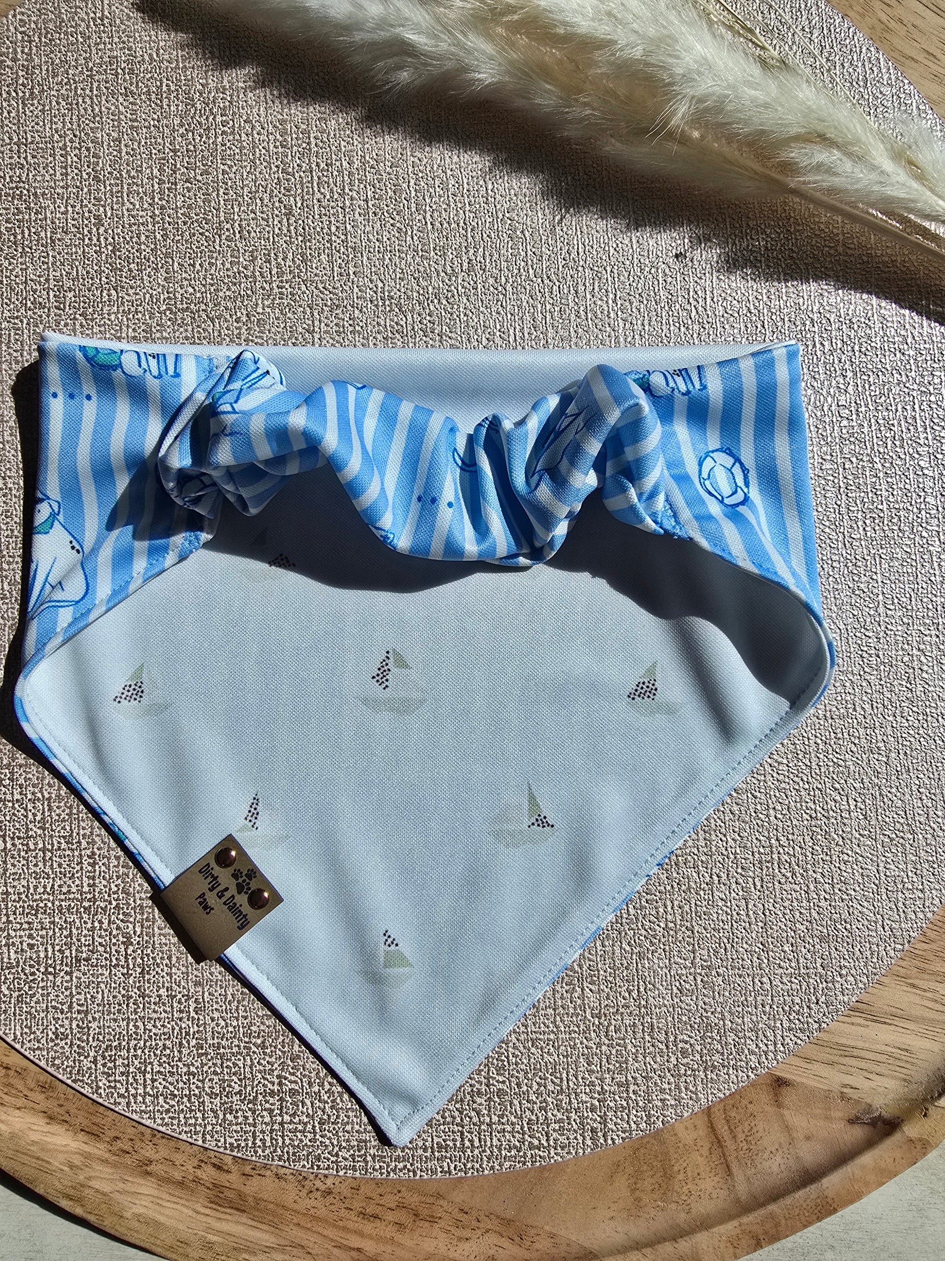 Blue and white striped bandana with embroidered design on a textured surface