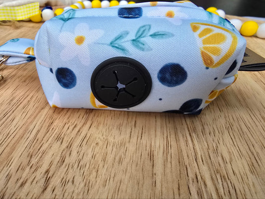Neoprene dog waste bag holder featuring a blueberry and lemon print with a built-in rubber dispenser opening and clip attachment for convenient walks. Handmade by Dirty and Dainty Paws
