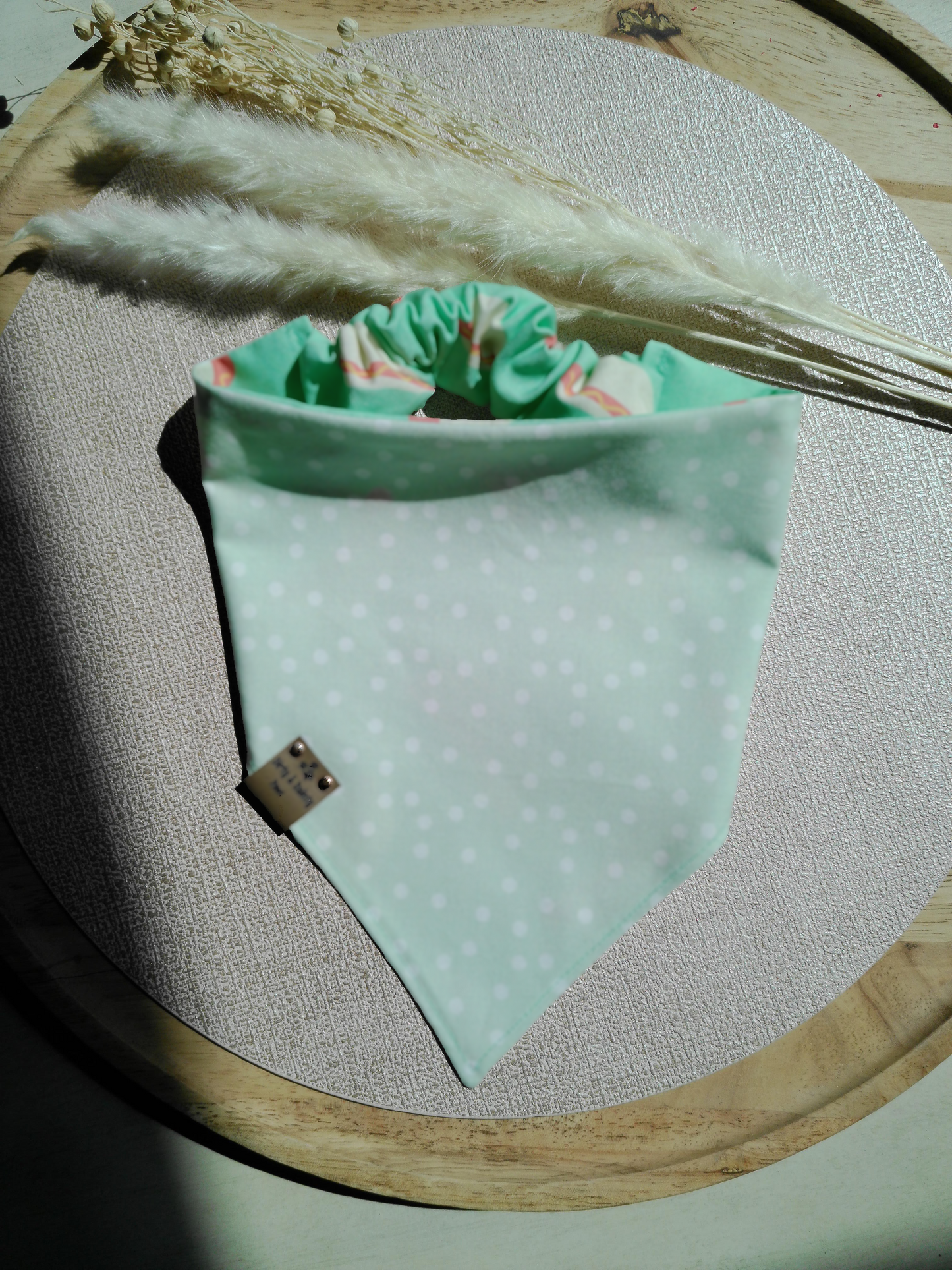 Light green fabric with white polka dots on a wooden embroidery hoop.