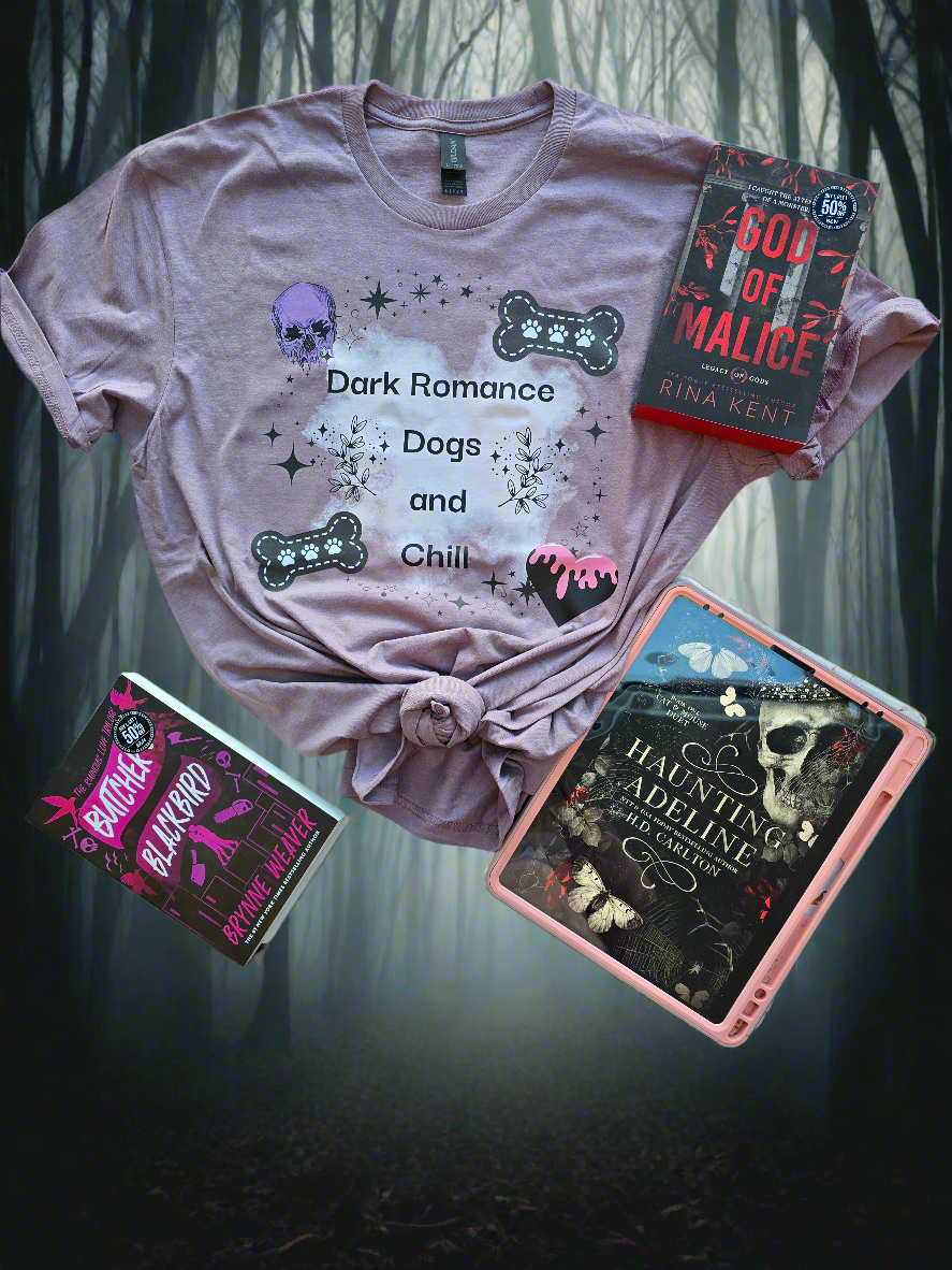 A soft mauve-colored t-shirt with the words "Dark Romance Dogs and Chill", featuring gothic-inspired designs like a skull, bones, and stars. Styled with dark romance books.