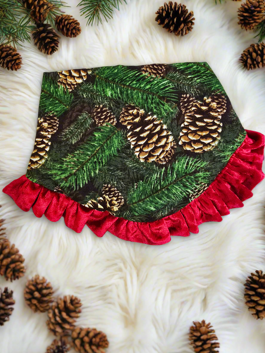  Dog wearing a Pinecone Ruffle Scrunchie Dog Bandana with a pinecone and evergreen design, accented by a red shimmering ruffle trim