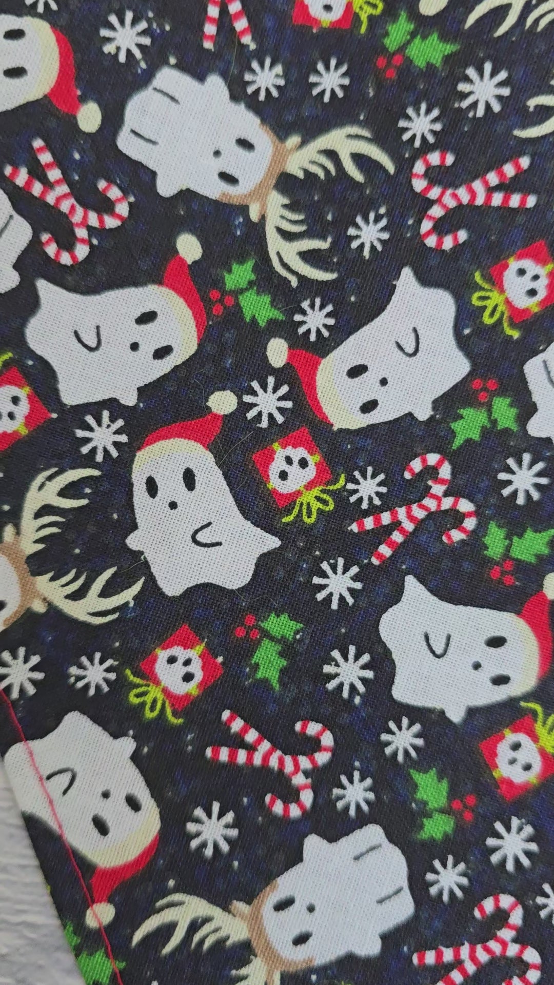 Reversible dog bandana with a "Ghosts of Spooky Christmas" print on one side and a shimmering red plaid design on the other