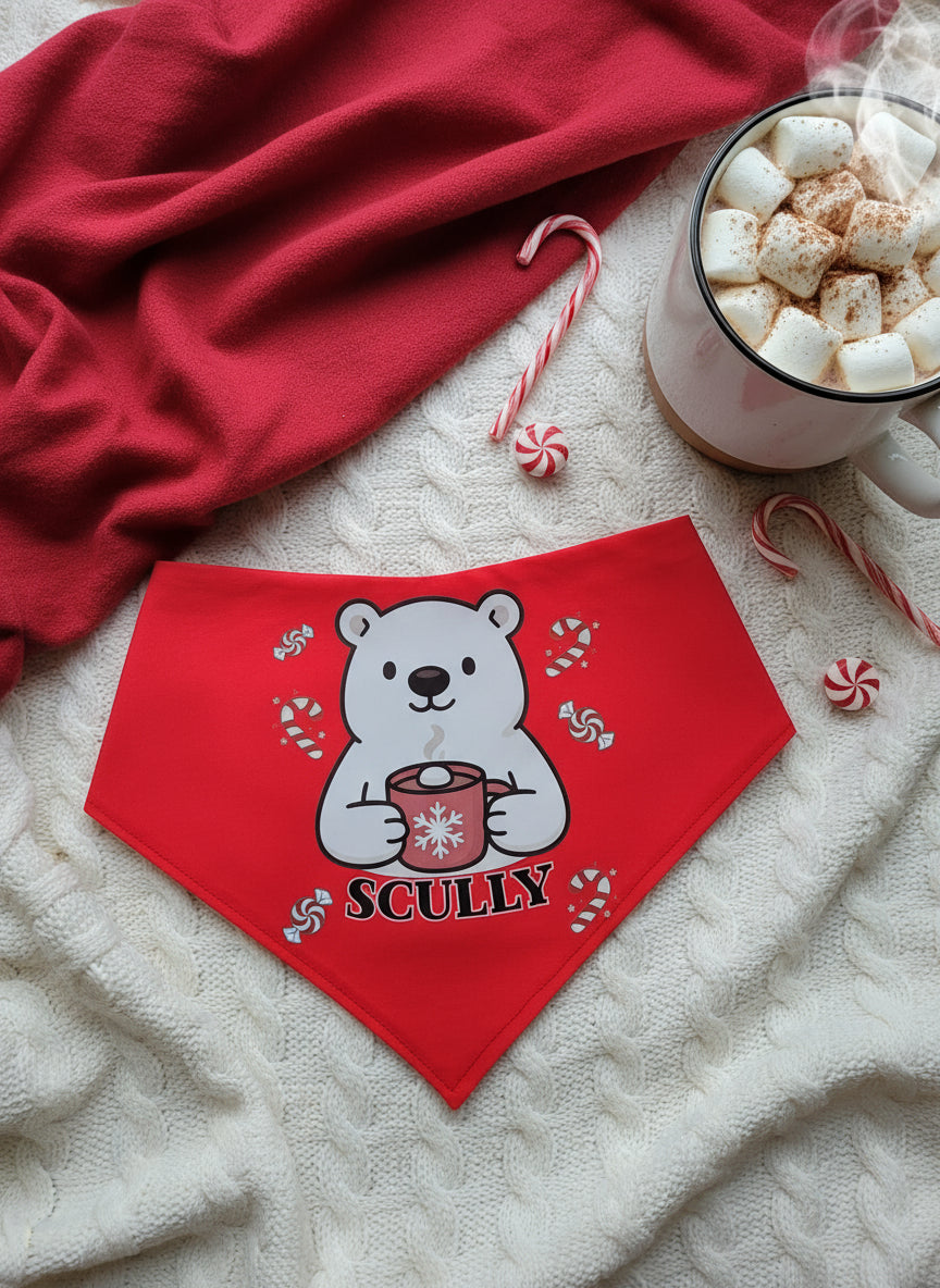 Red bandana with a polar bear design and 'Scully' text on a textured surface with hot chocolate and candy canes.