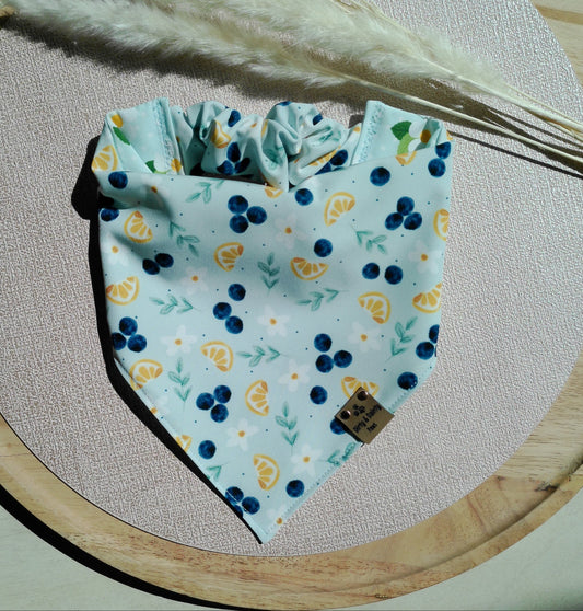 Fabric bandana with blueberries and yellow flowers on a wooden board with dried plants.