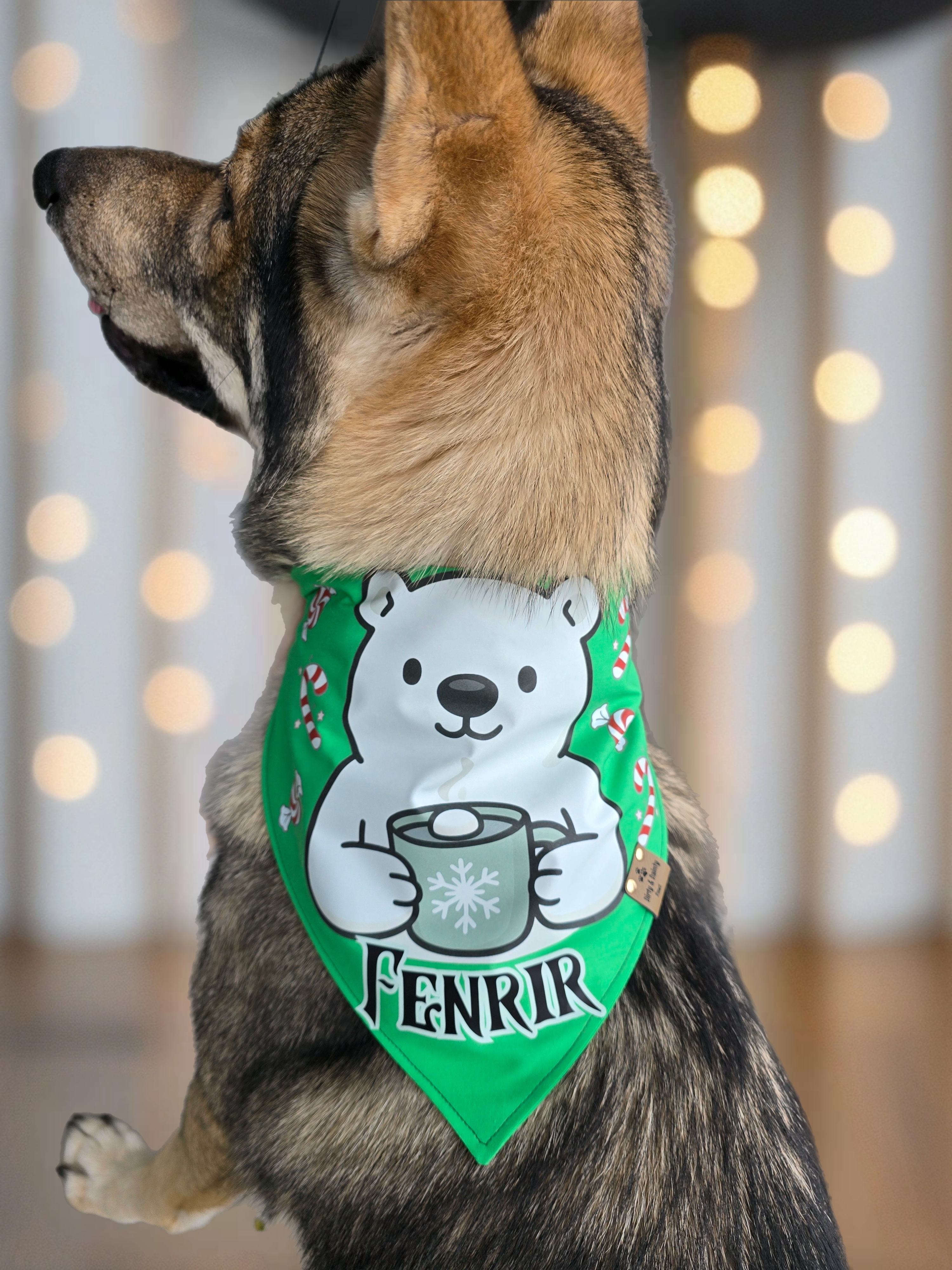 Dog wearing a green bandana with a polar bear design and 'Fenrir' text, against a blurred light background.