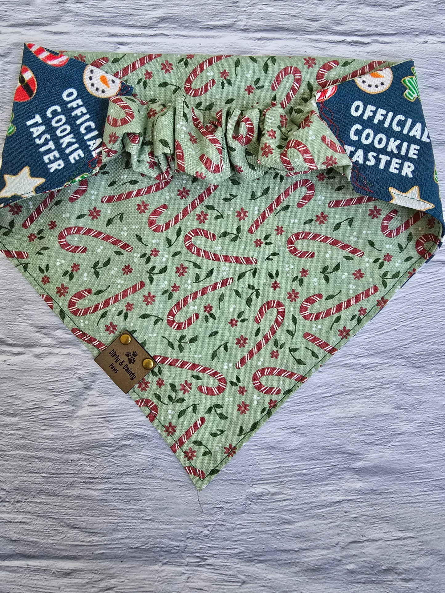 Reversible dog bandana with "Official Cookie Taster" print featuring holiday cookies, candy canes, and Christmas flowers.