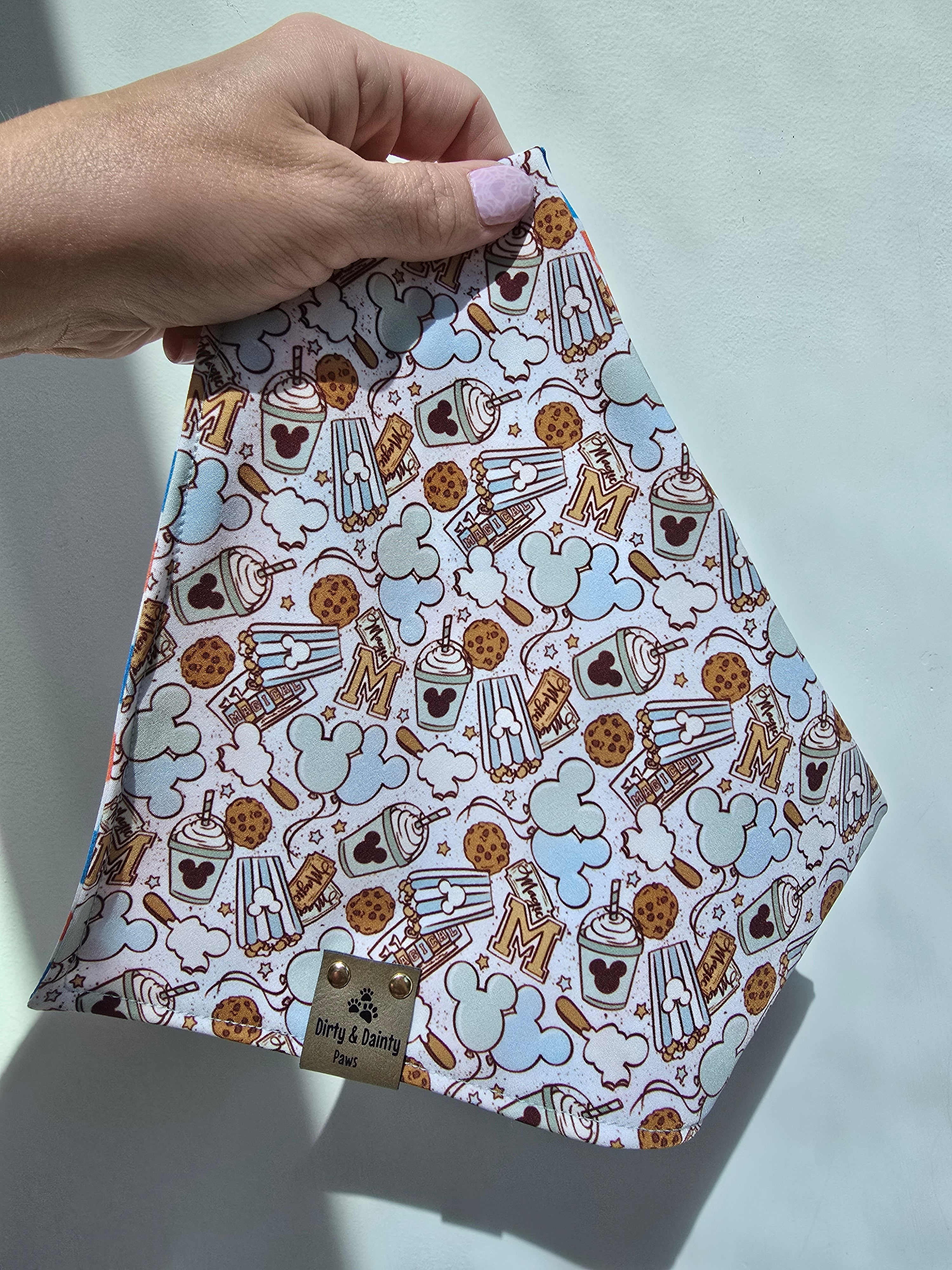 Close-up of Magical Treats Disney-inspired dog bandana with faux leather Dirty & Dainty Paws tag, made with Zoomie Proof™ polyester fabric.