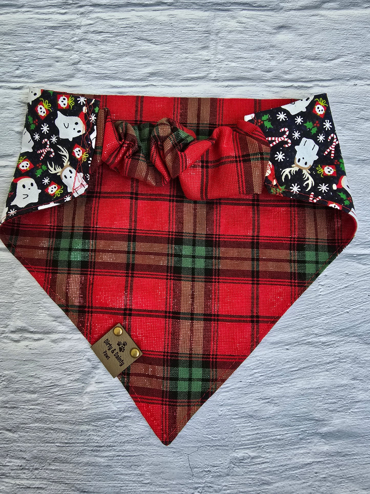 Reversible dog bandana with a "Ghosts of Spooky Christmas" print on one side and a shimmering red plaid design on the other