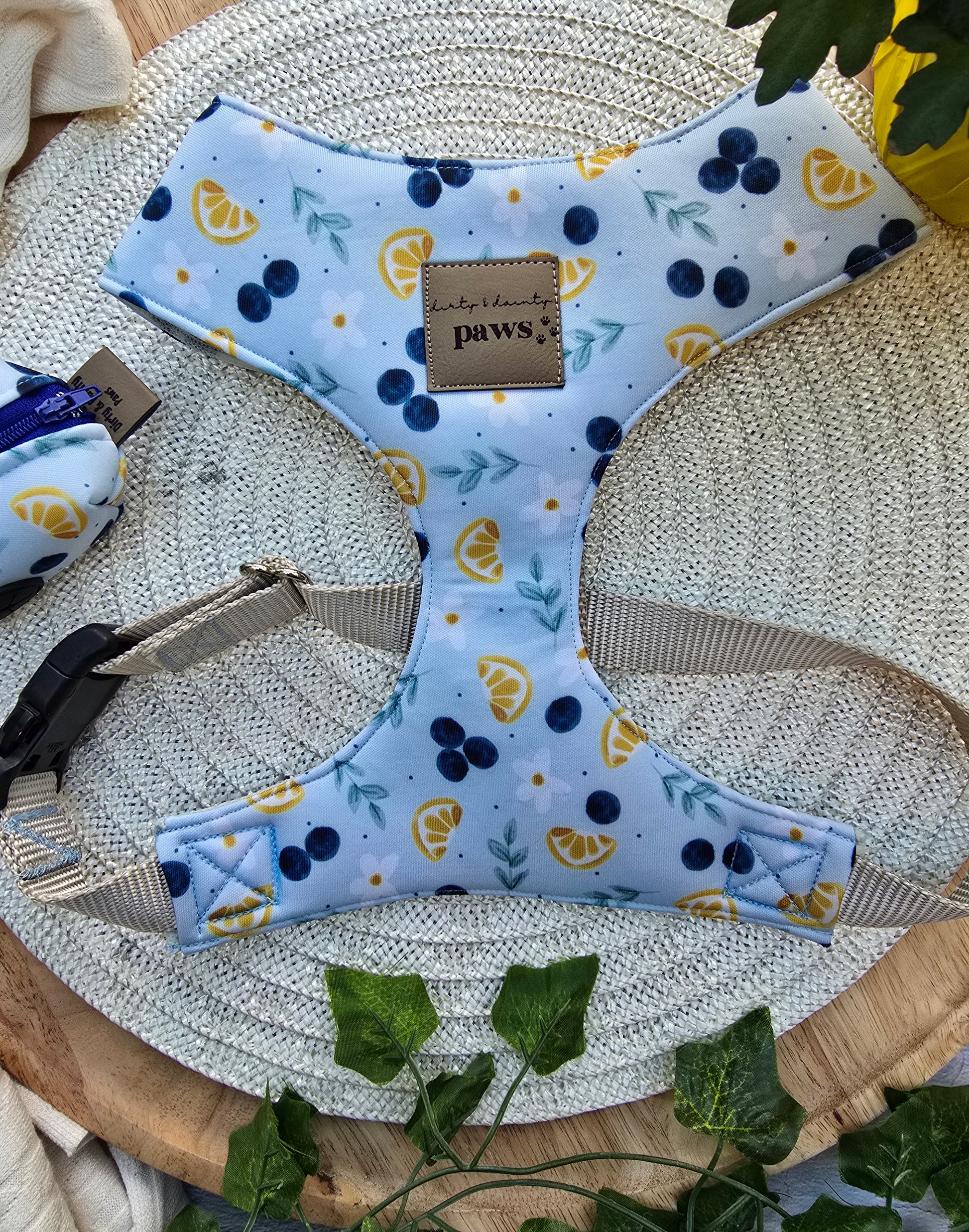 Dog harness with blueberry and lemon pattern on a wooden surface with greenery