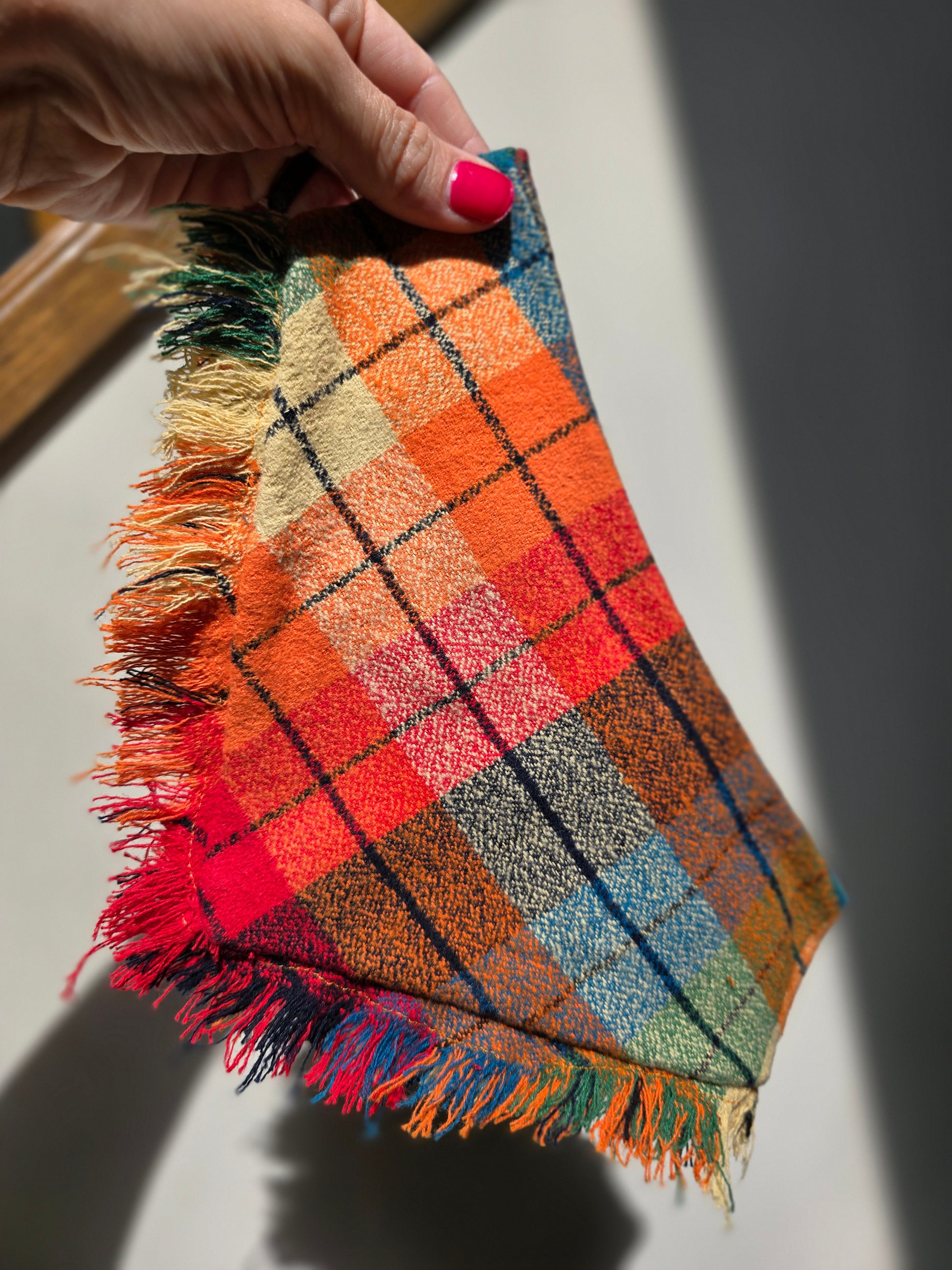 Colorful plaid dog bandana made from high-quality flannel, featuring hand-fringed edges, a secure snap closure, and a faux leather logo tag. Perfect for fall, the bandana showcases a vibrant mix of autumnal colors.